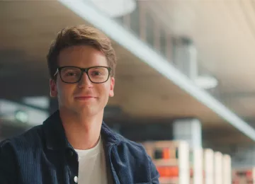 Estudiante con gafas mirando a cámara en bliblioteca